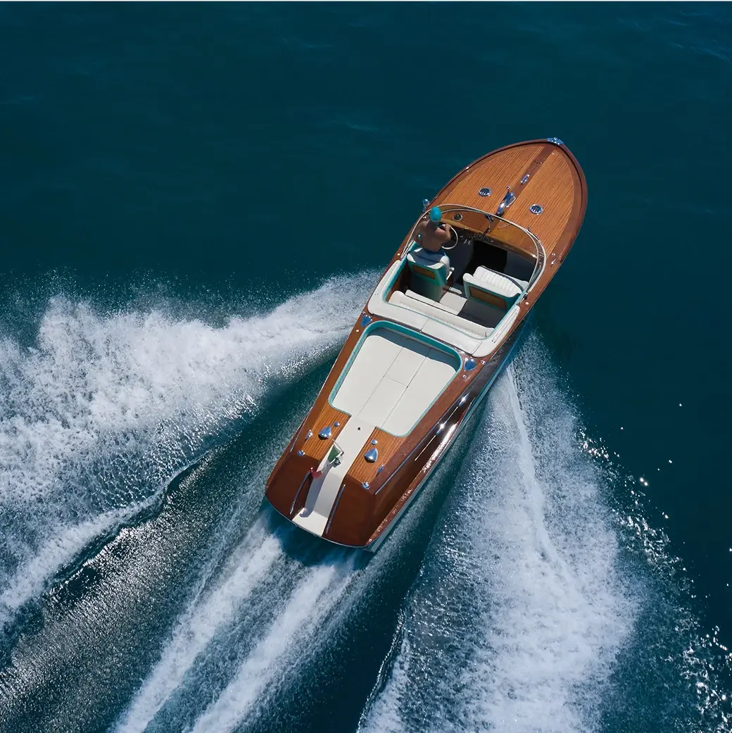 Wooden speedboat gliding across deep blue water, leaving a trail of white wake
