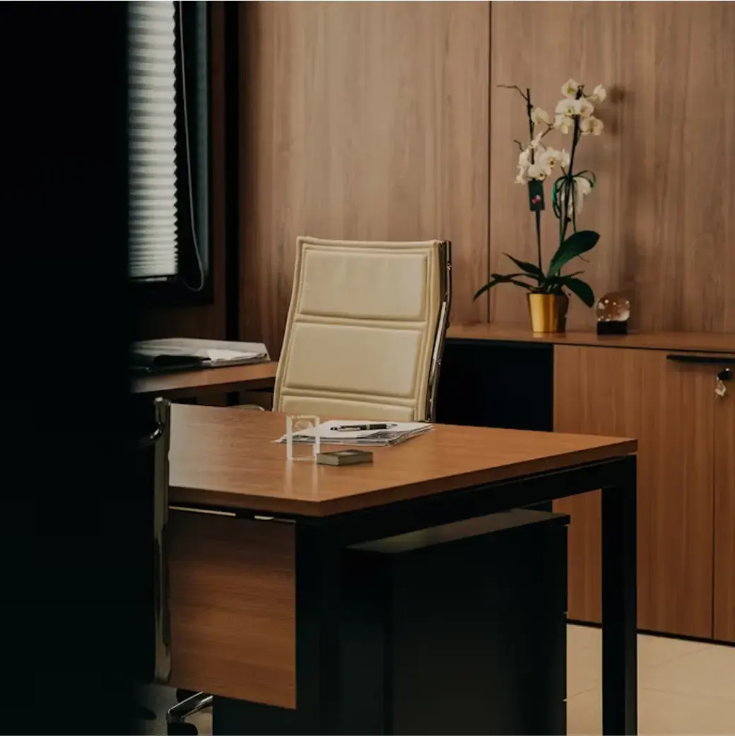Modern office with a wooden desk, beige chair, and orchid plant in a minimalist setting.
