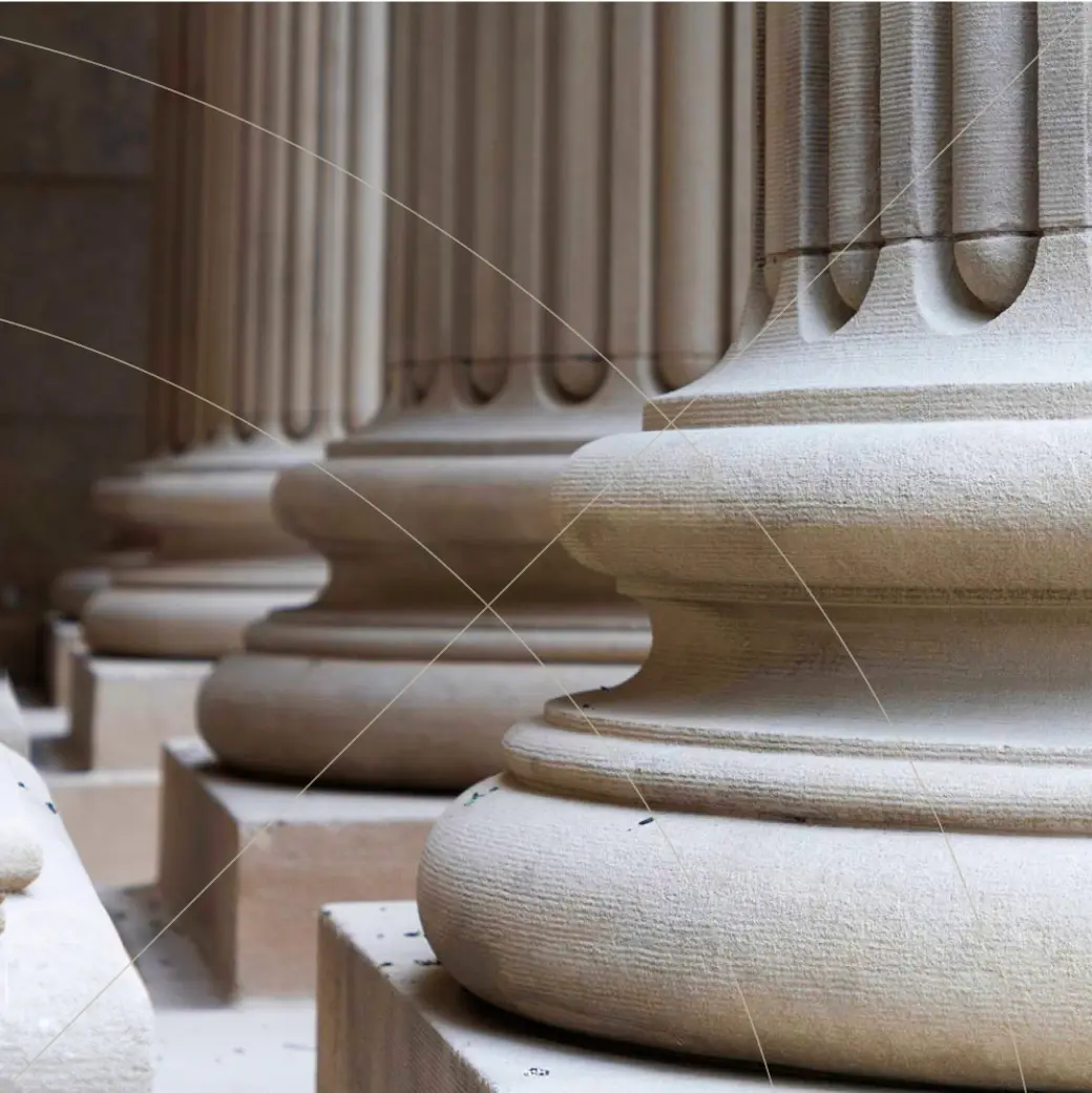 Row of large classical stone columns viewed from the base, showing smooth rounded pedestals and vertical fluting in soft light.